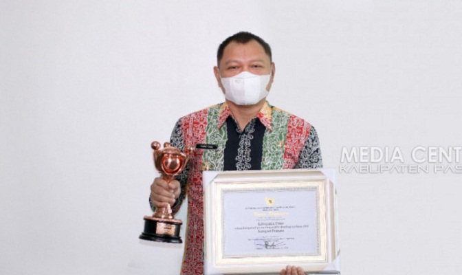 Bupati Paser menunjukkan penghargaan APE 2021 di ruang kerjanya,